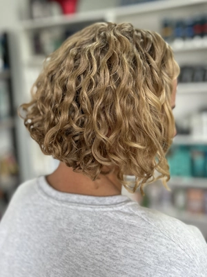 Shoulder-length honey blonde curls by Alexis